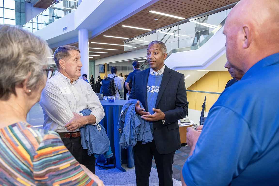 The dean of the School of Science and Engineering talks with attendees at an open house.