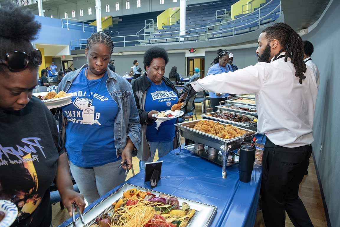 Attendees at 博彩网址大全's 2024 BAA Family reunion go through a buffet line. 